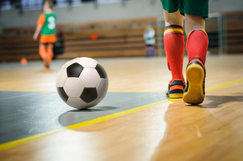Legs of a soccer player going toward a soccer ball indoors
