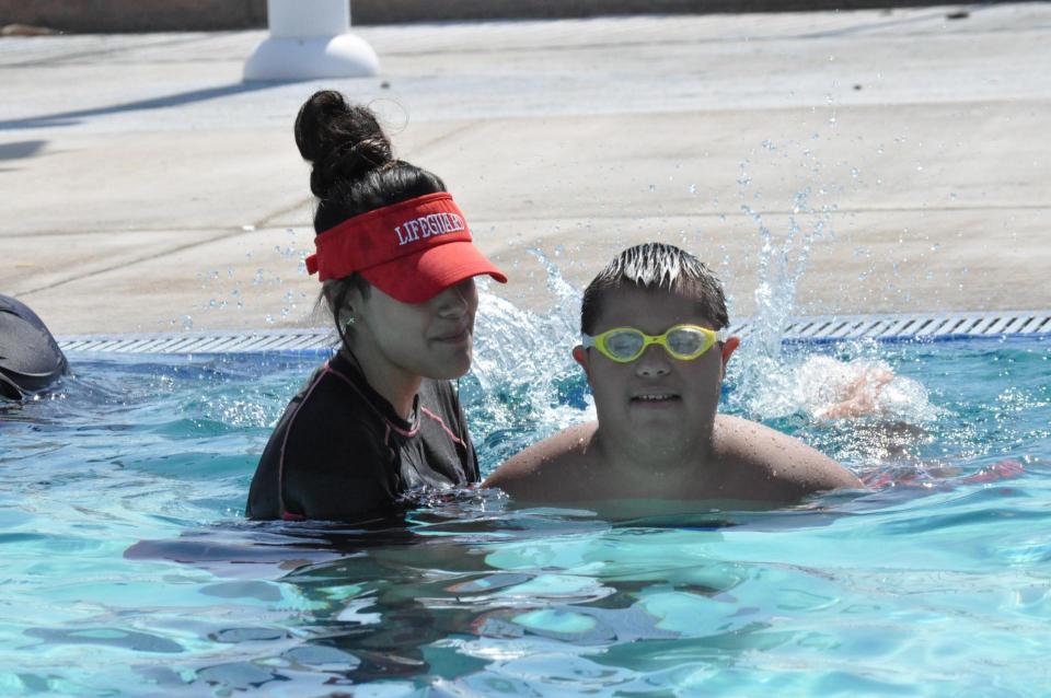 Adult helping child with special needs learn to swim in pool