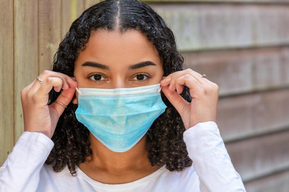 Teenage girl putting on medical mask