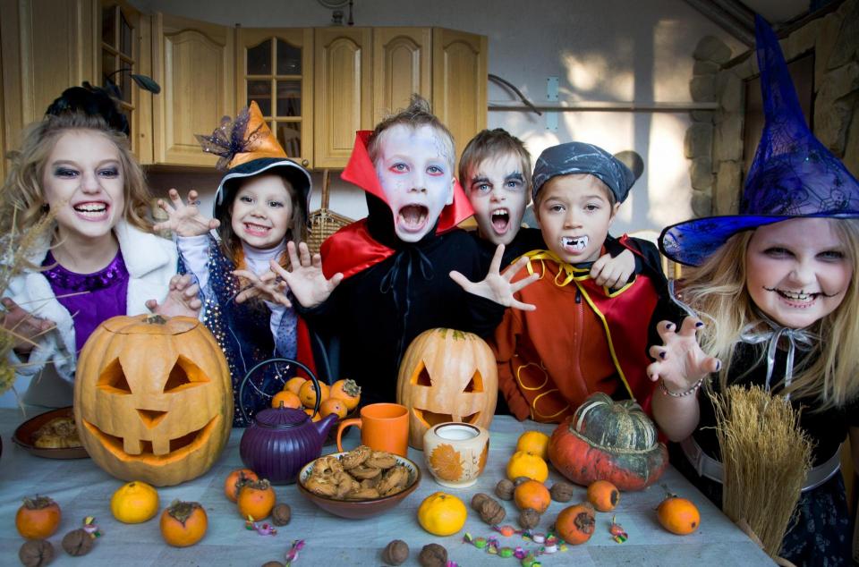 Photo of kids in costumes around pumpkins