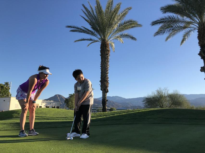 Photo of golf instructor with student putting