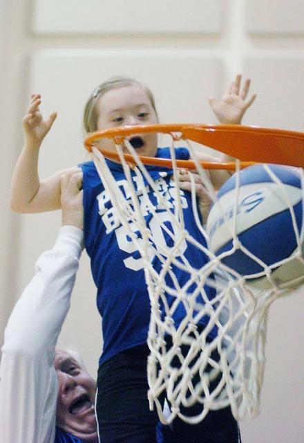 Little boy being lifted to make basketball shot indoors