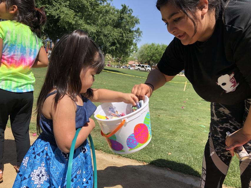 Little girl being given Easter eggs at egg hunt