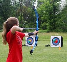 Teen girl shooting a bow and arrow at a target