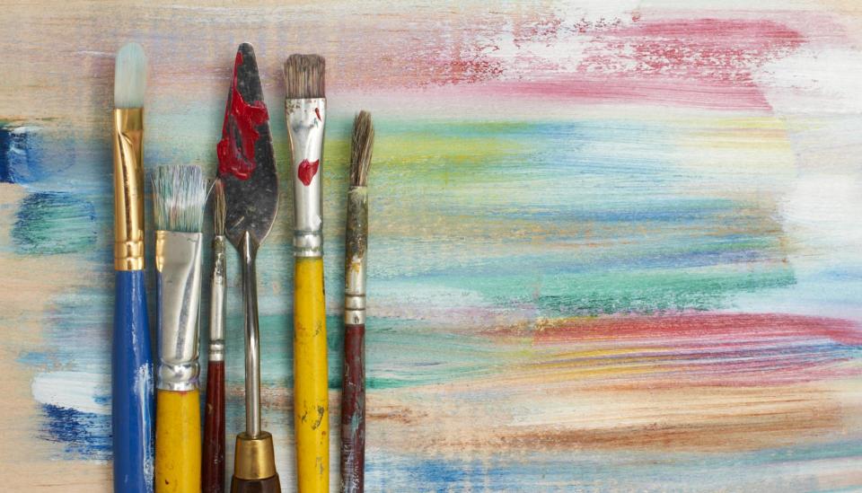 Paint brushes against an abstract art piece