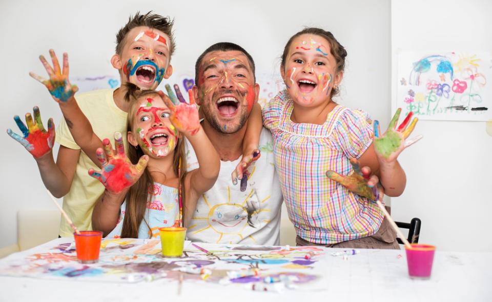 Photo father with his son and two daughters laughing, painting and getting messy