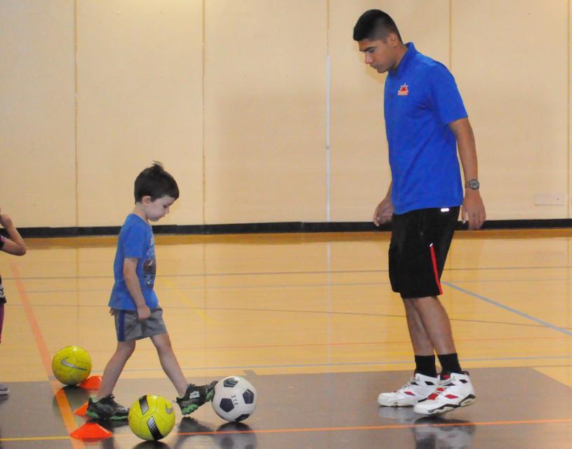 Child and adult with soccer ball practicing indoors