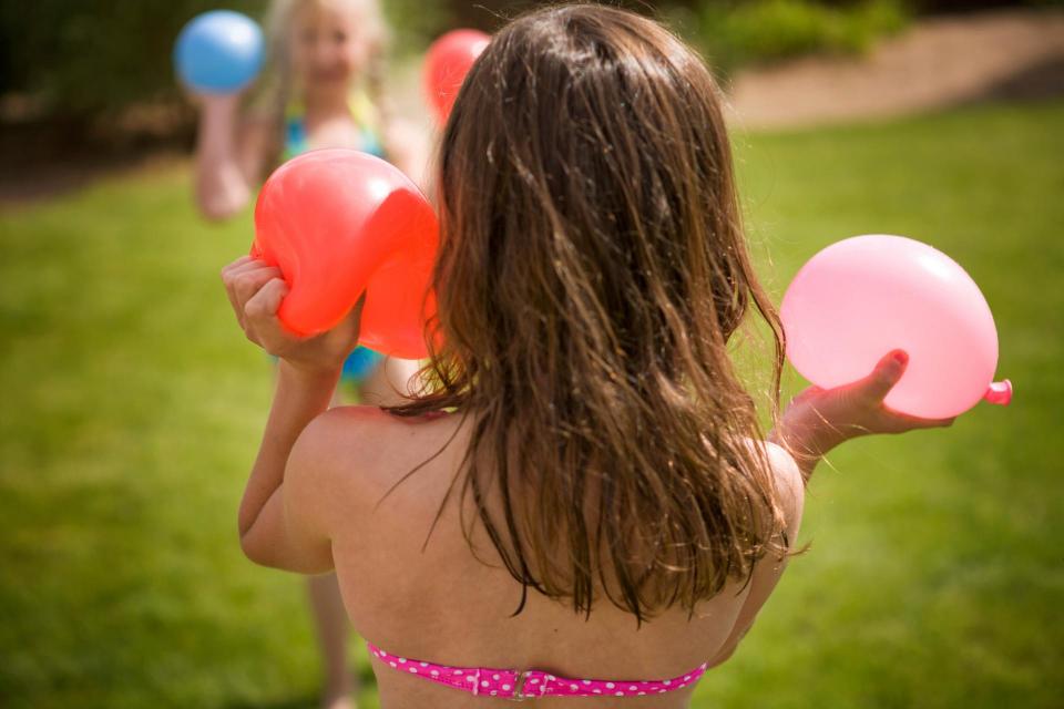 Back of girl holding water balloons