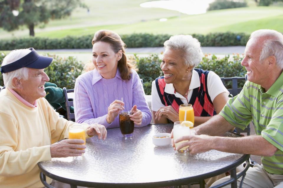 Four senior adults enjoying refreshments in a park