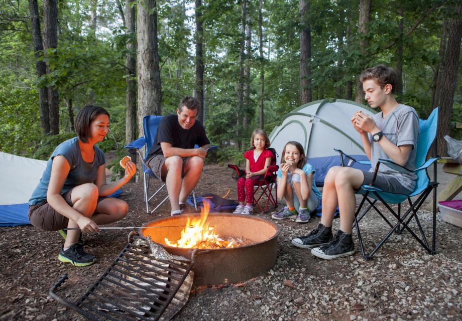 Group of five people, kids and adults, around a campfire