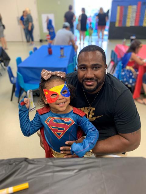 Young girl dressed as super hero with her father