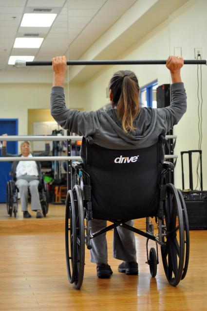Woman raises barbell over her head photo