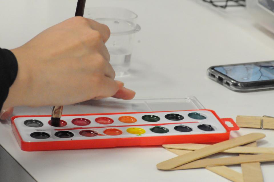Hand of child dipping brush into paint