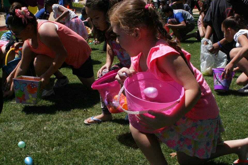 Little girl in pink dress gathering Easter Eggs