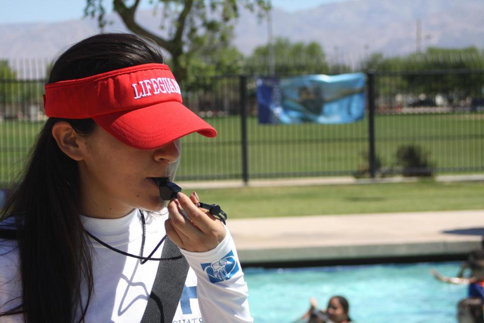 Close up of female lifeguard blowing a whistle